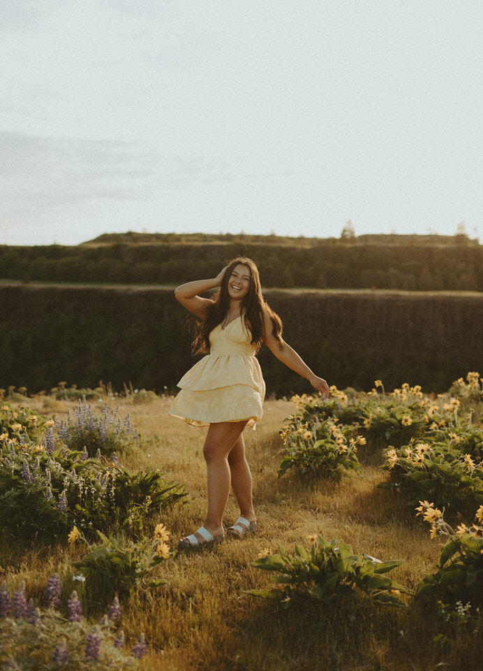 Young woman laughing in a field of yellow flowers at sunset