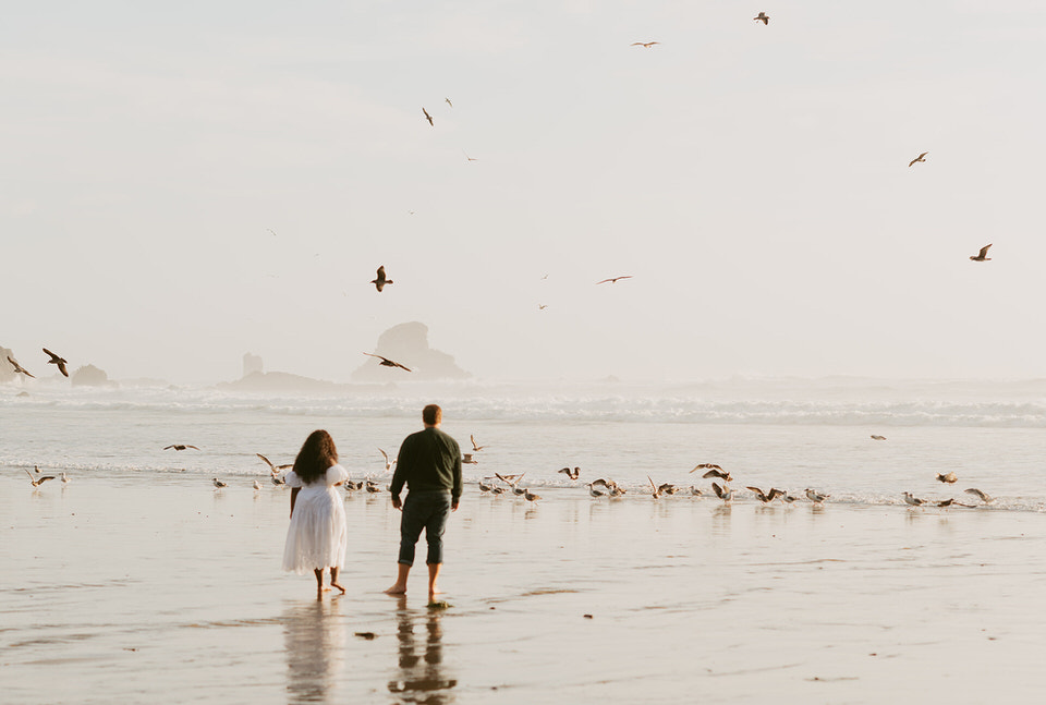 Oregon beach engagement at sunset with tons of birds on the shore.