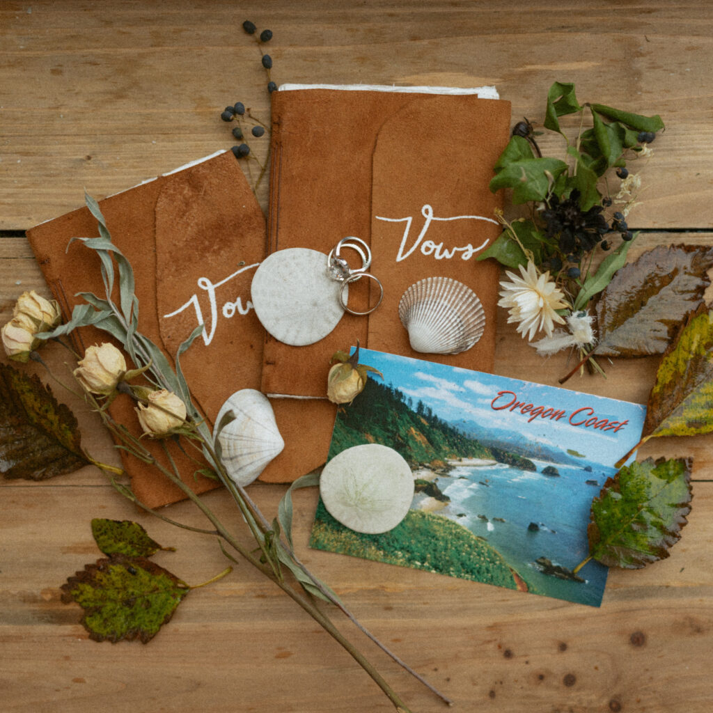 wedding rings and vow books with seashells and flowers sitting on a table