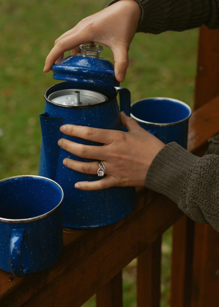 Hands opening the blue pot sitting on the railings of a wood cabin