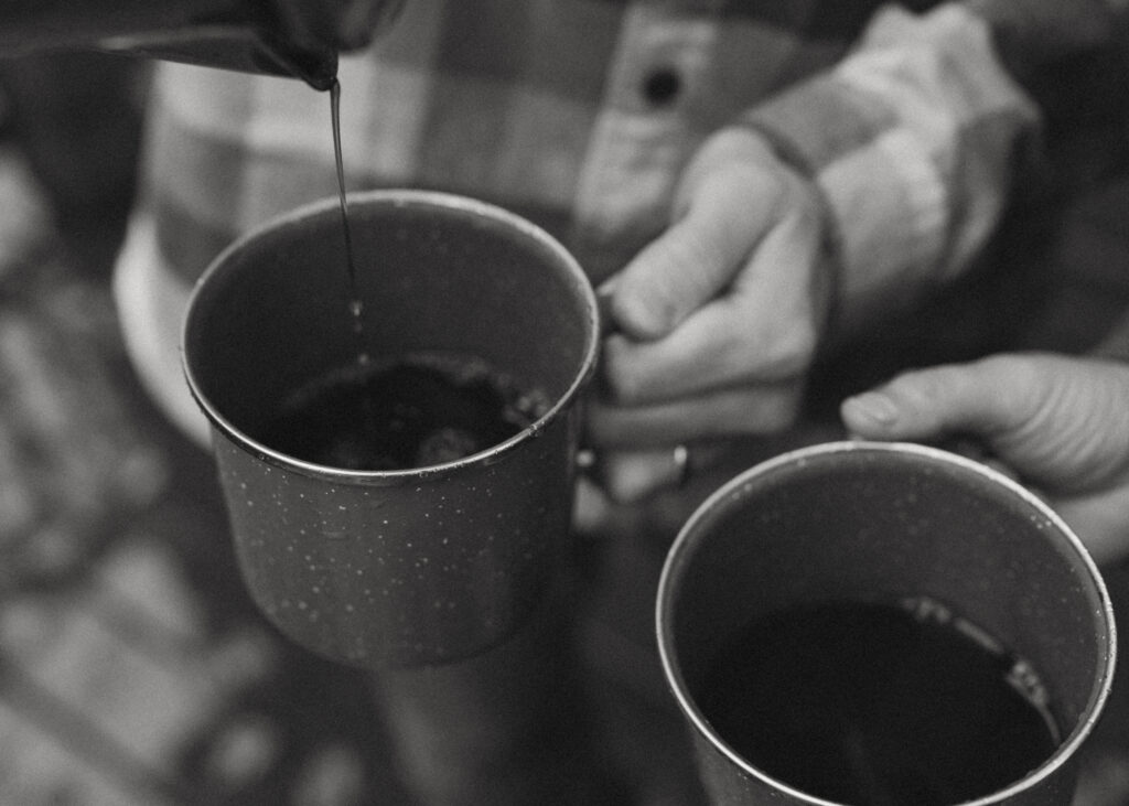 Black and white photo of a hot coffee being poured into a cup