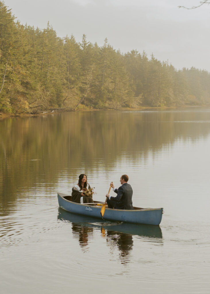 Sweet couple sitting across each other, and the groom paddling across the serene lake for their dreamy elopement