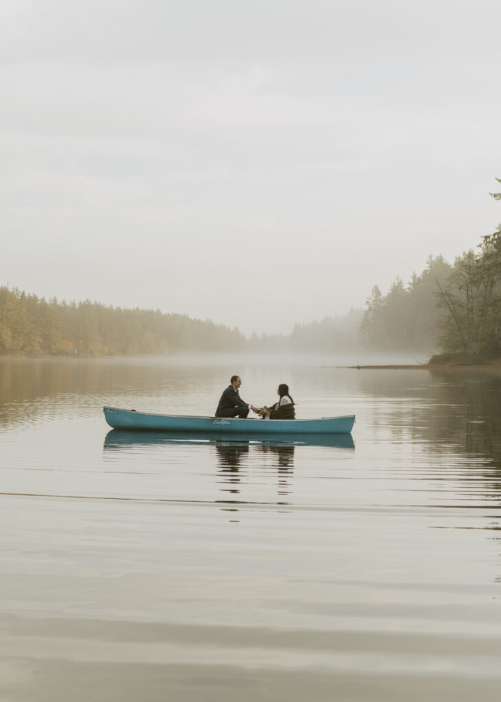 Newlywed couple sitting across each other in a canoe on the lake for their dreamy elopement