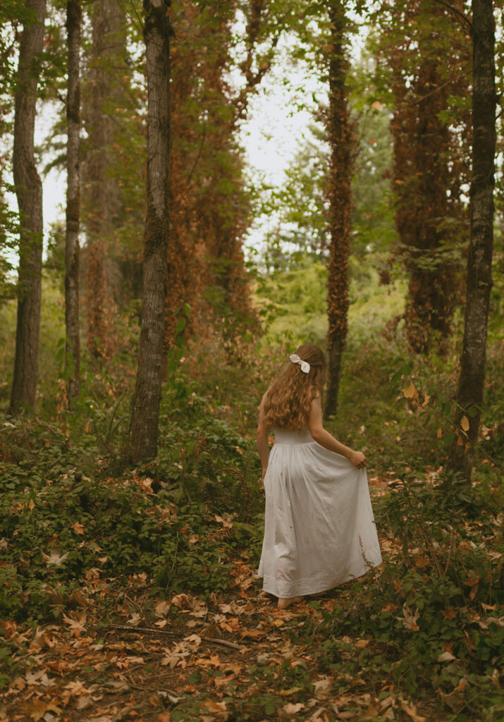 Young woman in her beautiful wedding dress walking along the forest surrounded by the tres