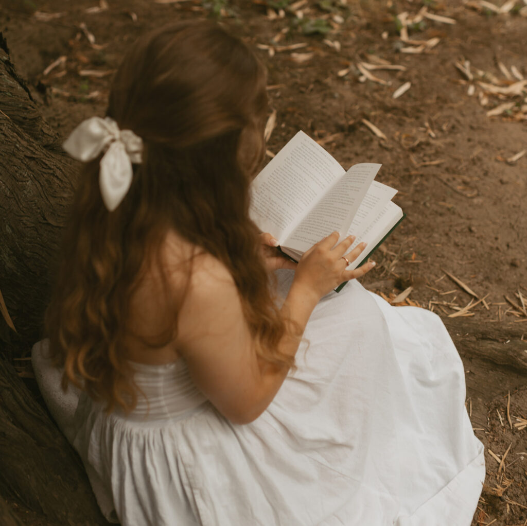 Young woman in a white dress reading a book