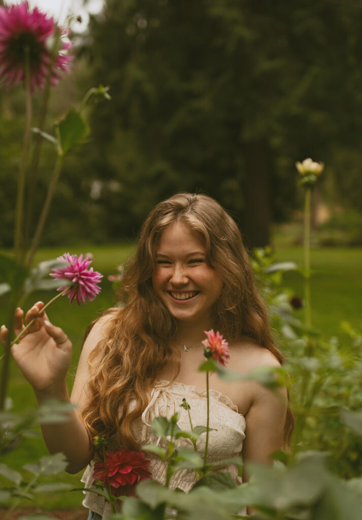 Young woman smiling, holding flowers in a lush garden
