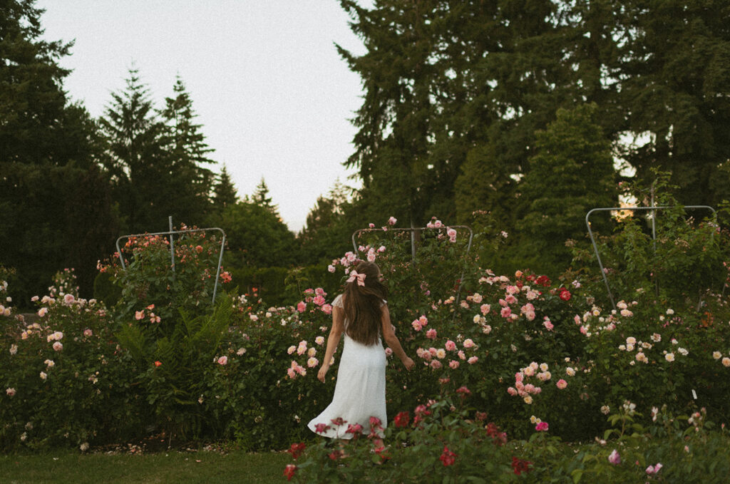 young woman having her Senior pictures in Portland, Oregon with a fully bloomed roses backdrop