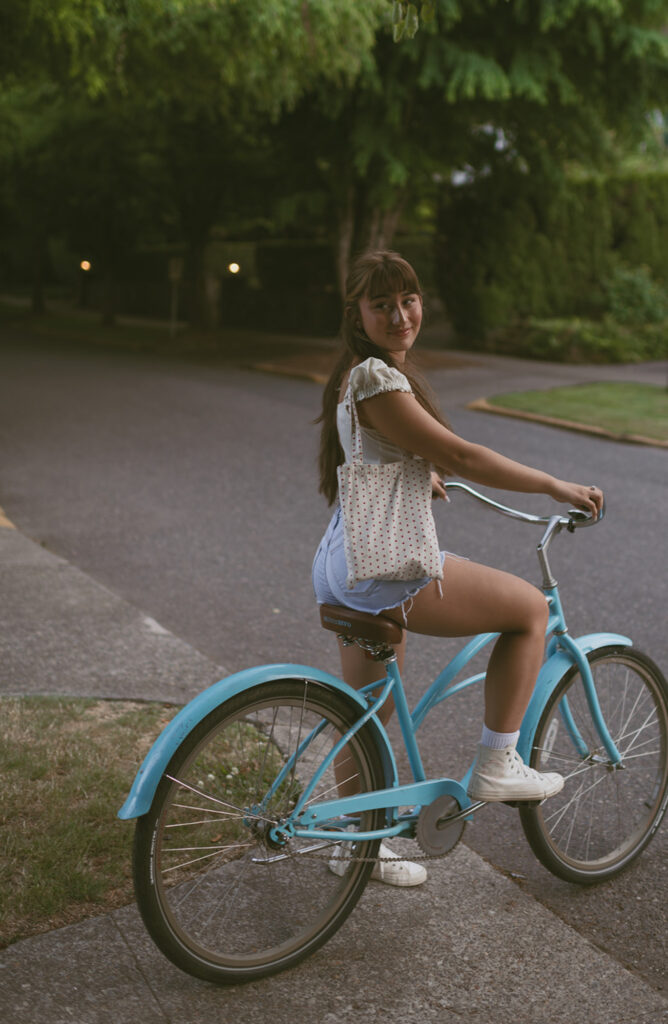 Young woman looking back while riding a blue bicycle wearing her tote bag