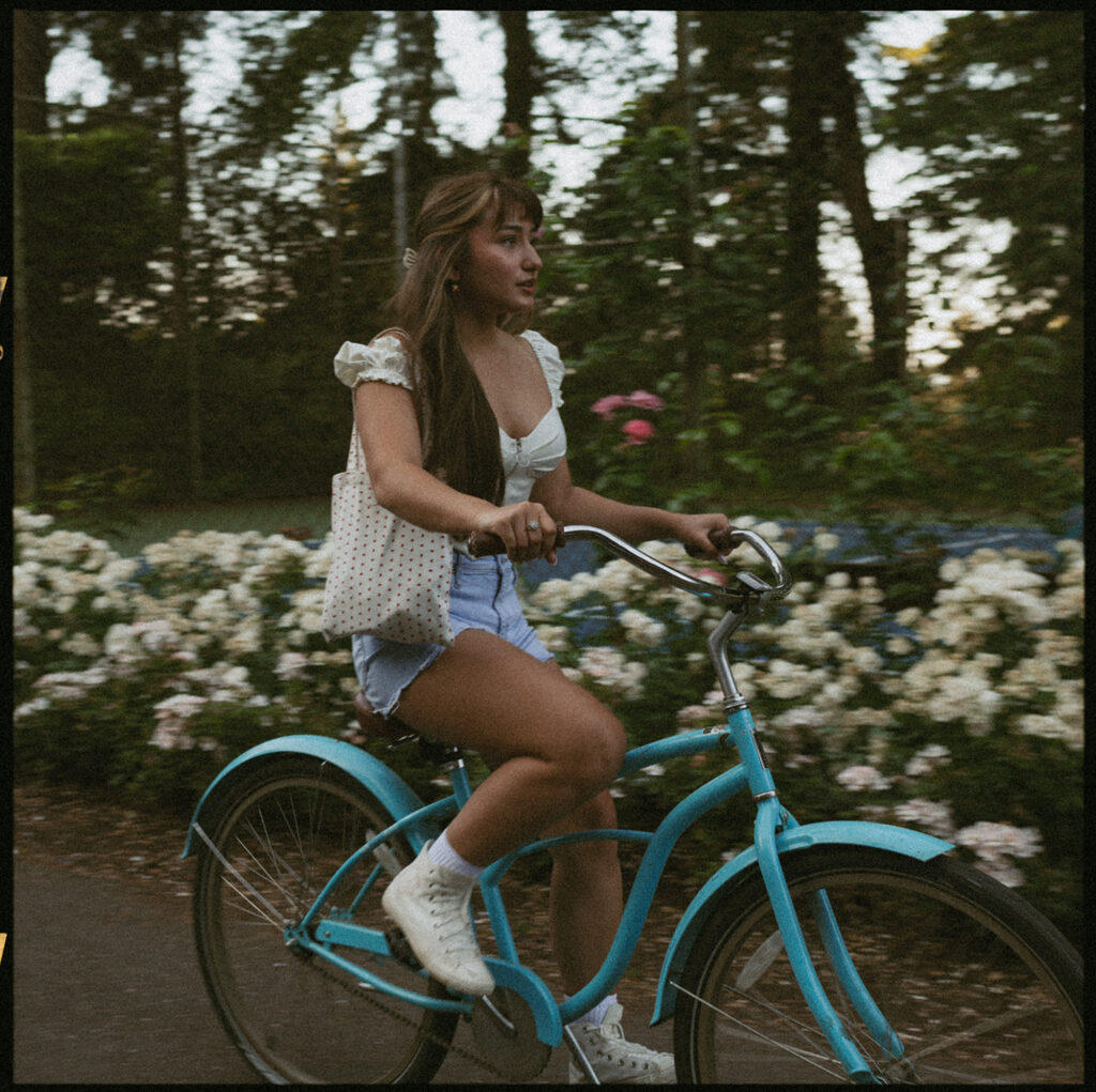 young woman riding a blue bicycle, carrying a tote bag