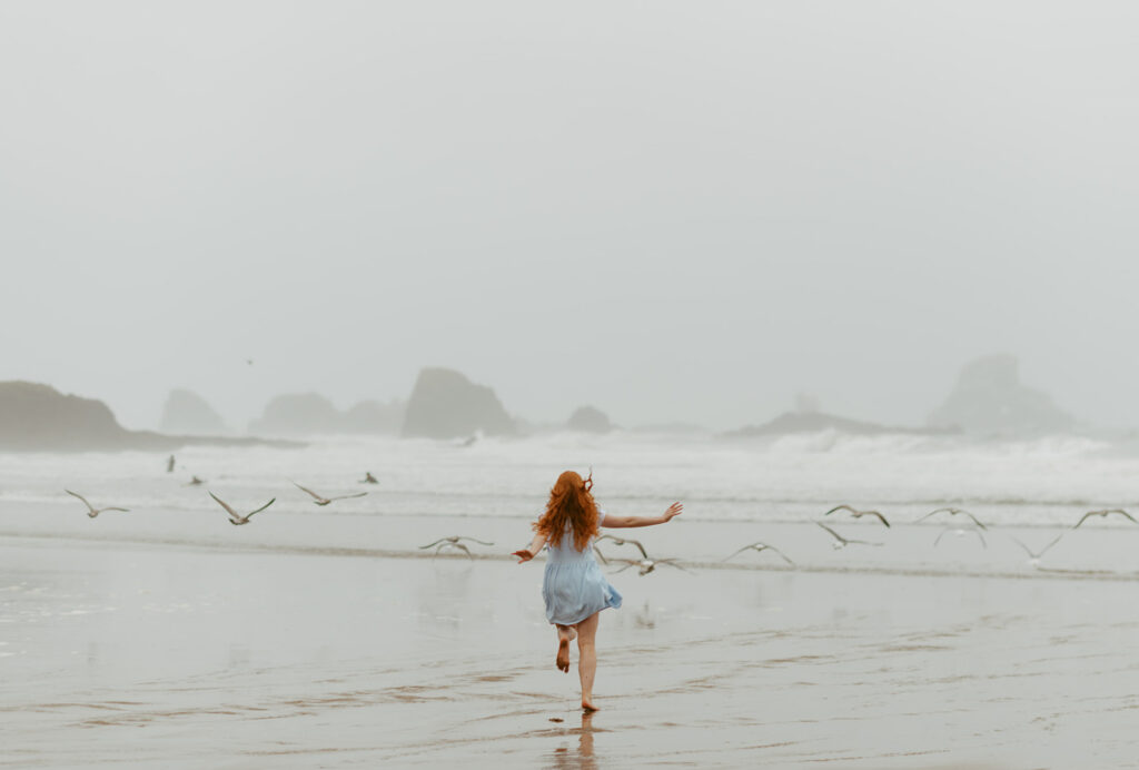 girl running along beach in Oregon