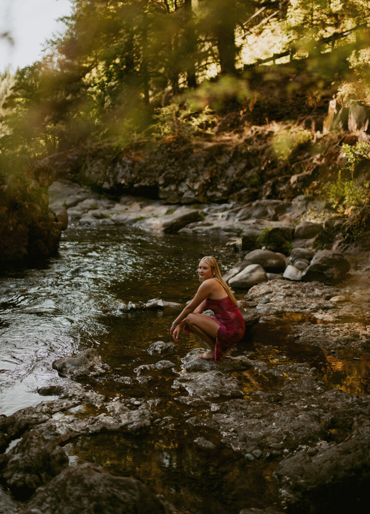 girl kneeling next to river in Oregon
