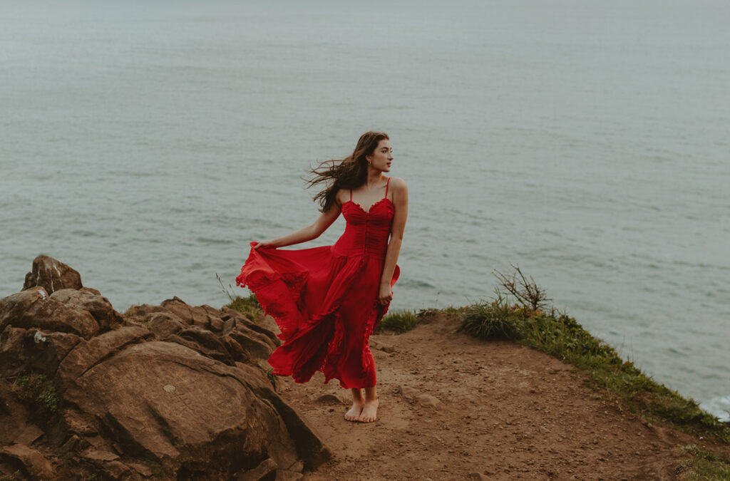 girl in red dress standing on cliffside in oregon
