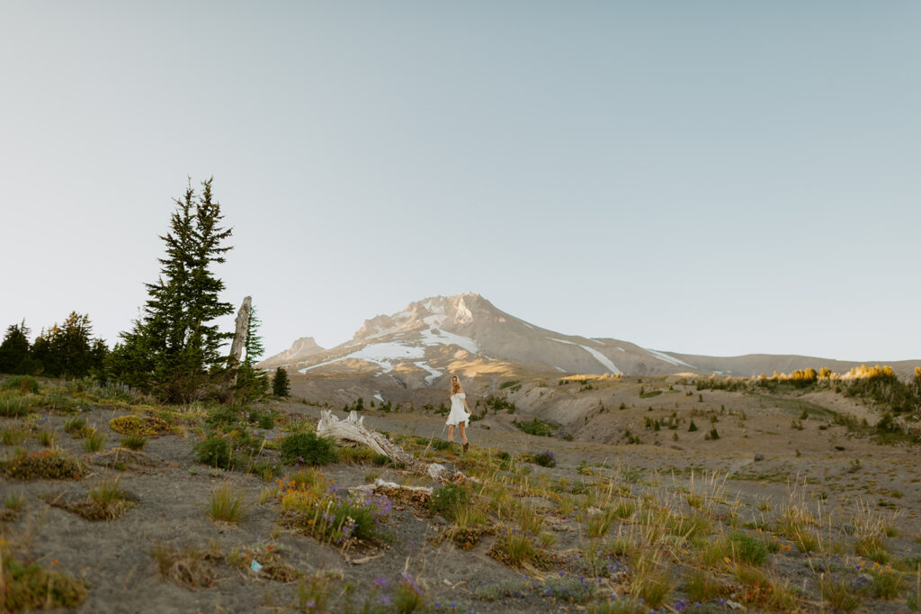 Woman in a white dress walking through a mountainous landscape at sunset in Oregon