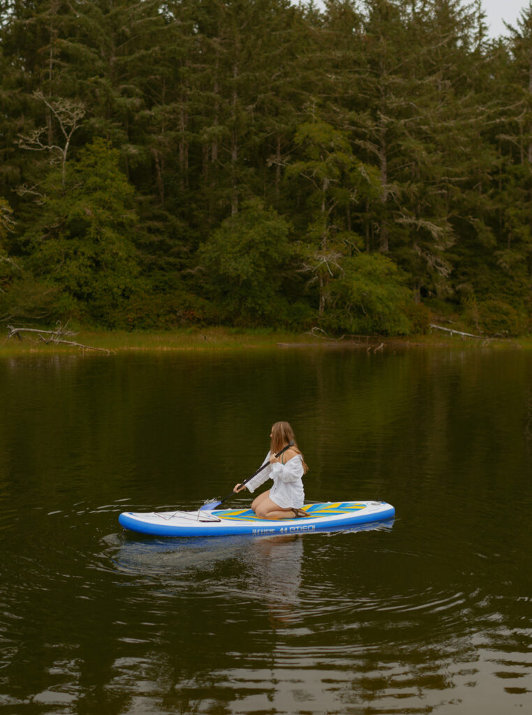girl in white shirt paddle boarding on a lake at the Oregon coast
