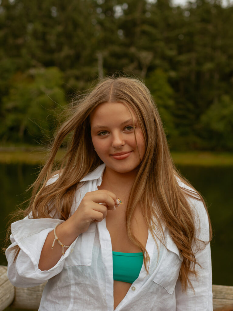 girl standing next to lake in white button up shirt