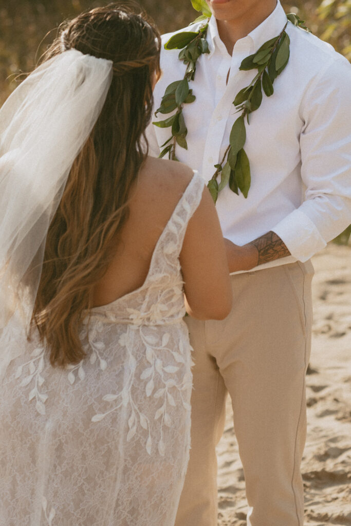 bride and groom on a sandy beach, facing each other on their wedding ceremony