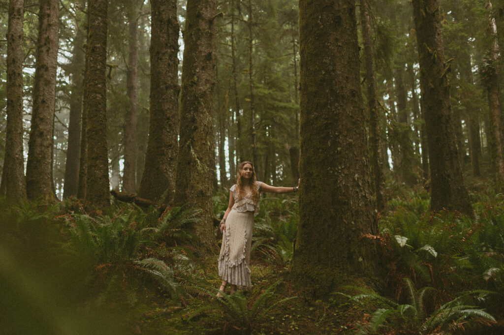 girl standing in woods at the Oregon coast in dress