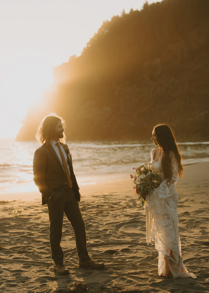 bride and groom standing on a sandy beach