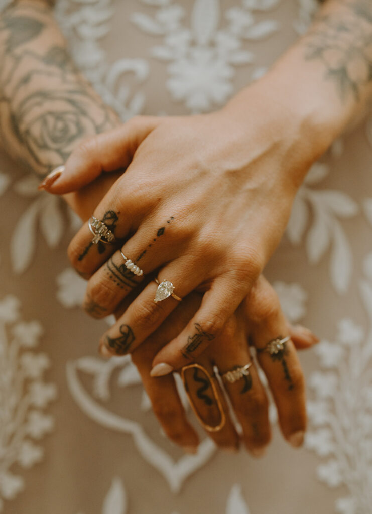 close-up image of tattooed hands with several rings with various designs