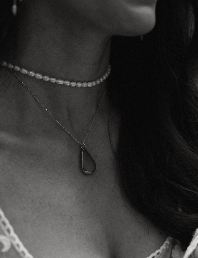 A close-up monochrome image of the bride's neck and part of her shoulder wearing two necklaces
