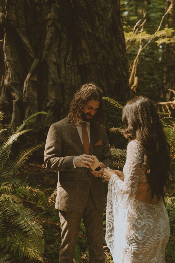 bride and groom standing in an outdoor forested setting facing each other
