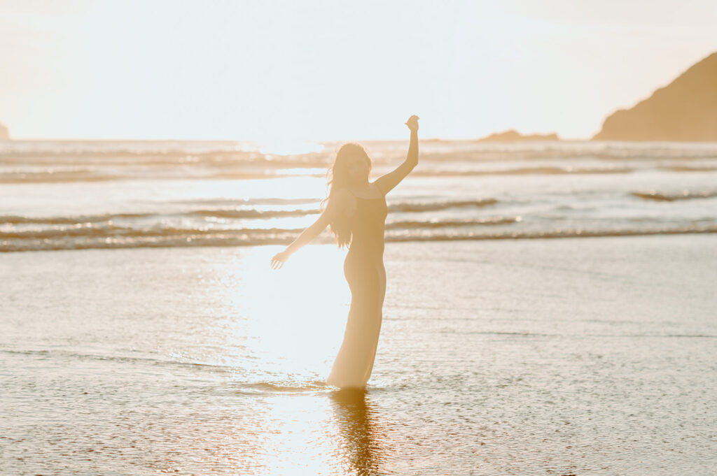 Lady standing in shallow water at the beach during sunset for beach senior photos