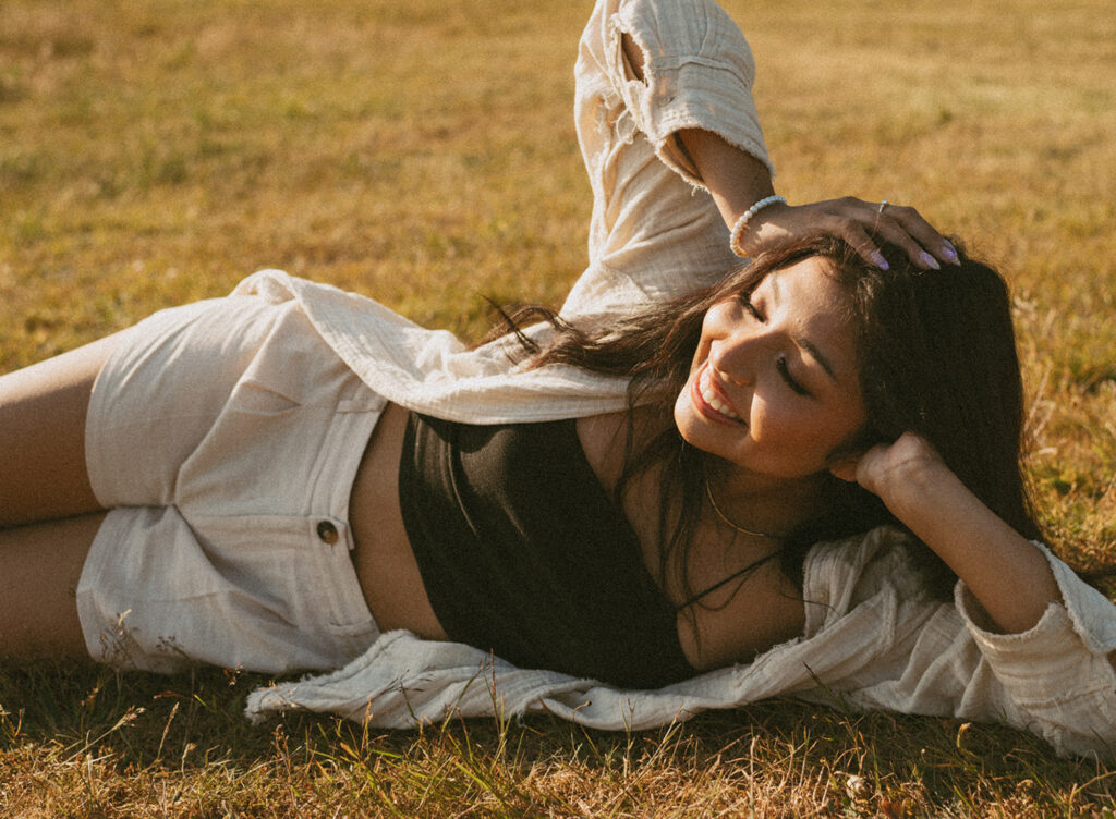 Woman lying on grass, smiling up at the camera