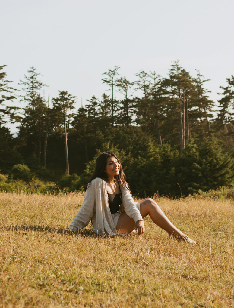 Woman sitting on grass with trees in the background