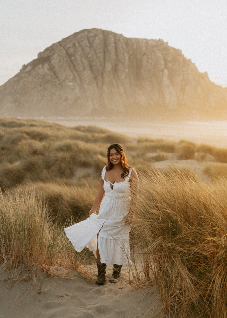 Lady in a white dress walking in a field of tall grass at sunset