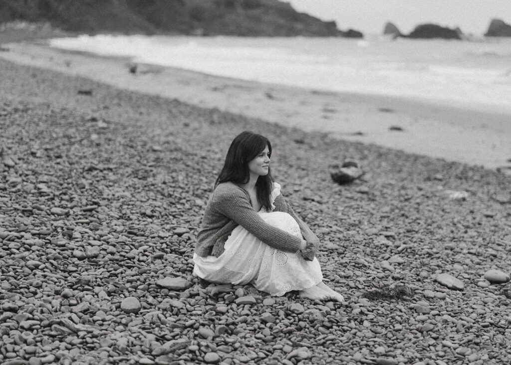 Woman sitting on beach rocks looking contemplative