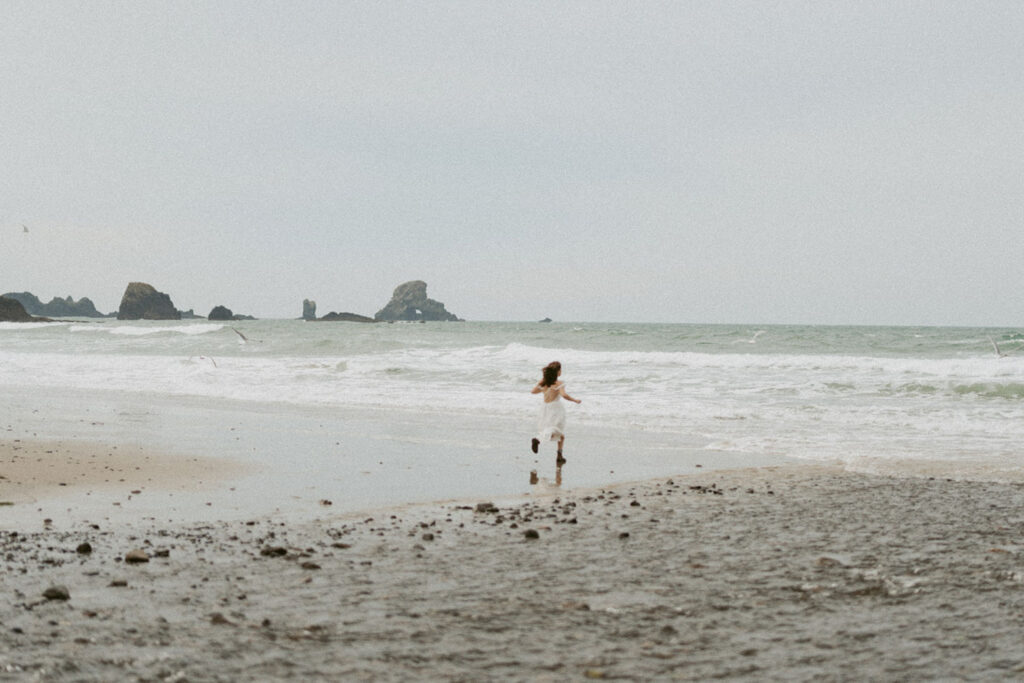 Woman running on a sandy beach for her senior session