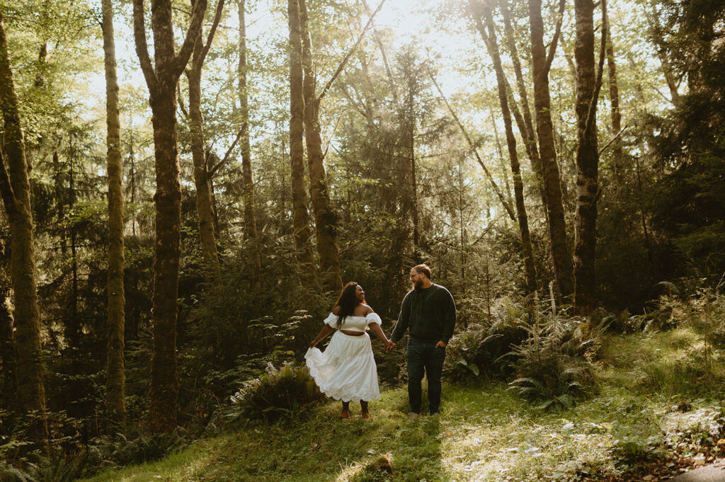 Couple walking hand-in-hand through a forest for na engagement session in Oregon