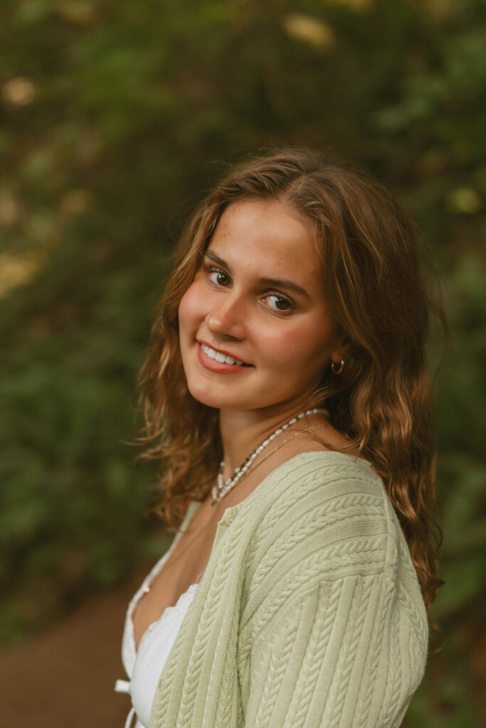 Portrait of a woman smiling in a forest setting for her senior session