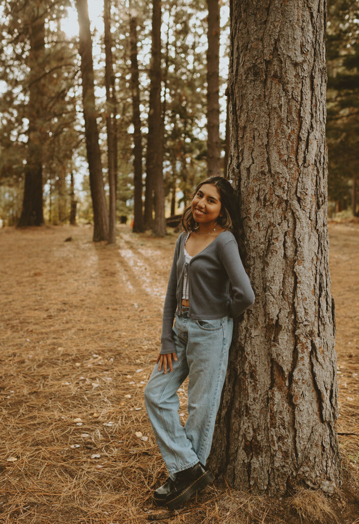 Senior girl leaning casually against a tree for a photo session by a senior photographer in Bend