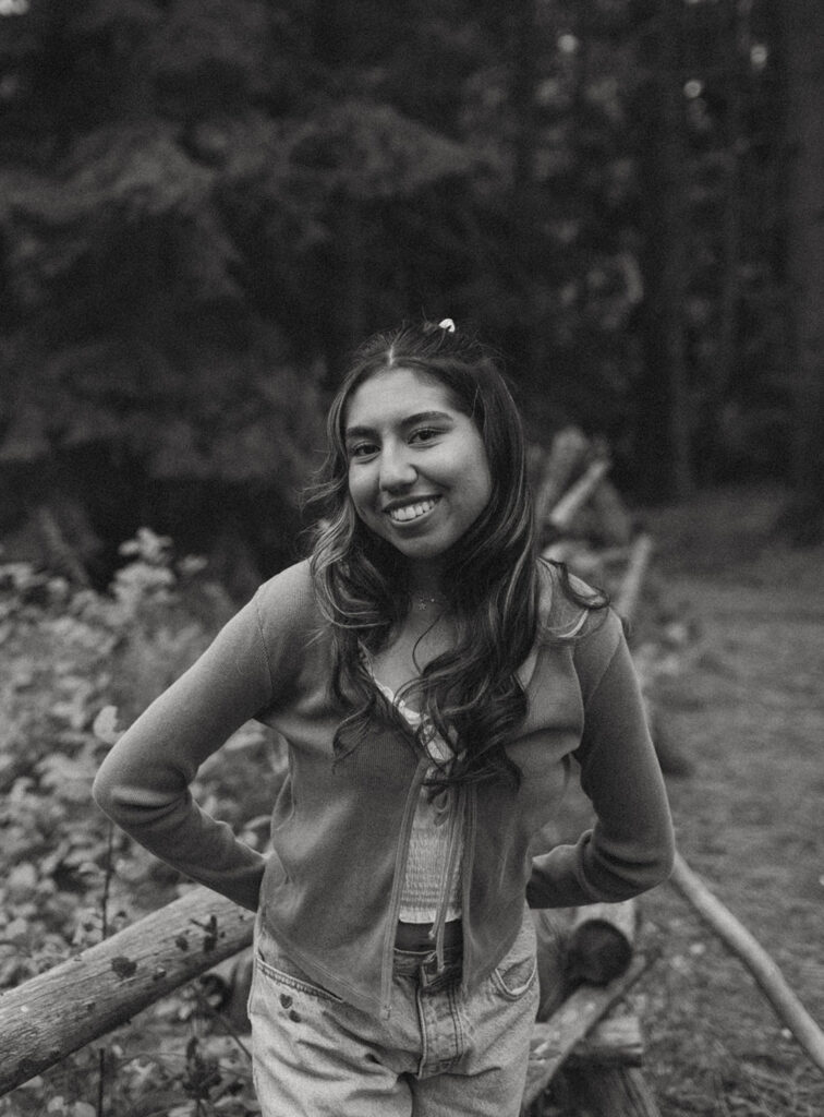 Black and white portrait of a senior girl leaning on a rustic wooden fence