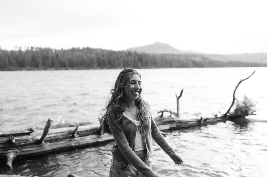 Black and white image of the senior girl smiling, water rippling behind her