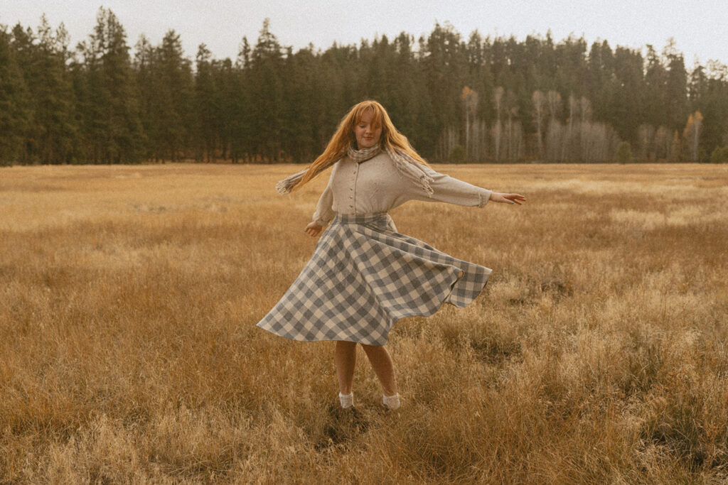 Senior girl twirling in a golden meadow with mountain views in Black Butte