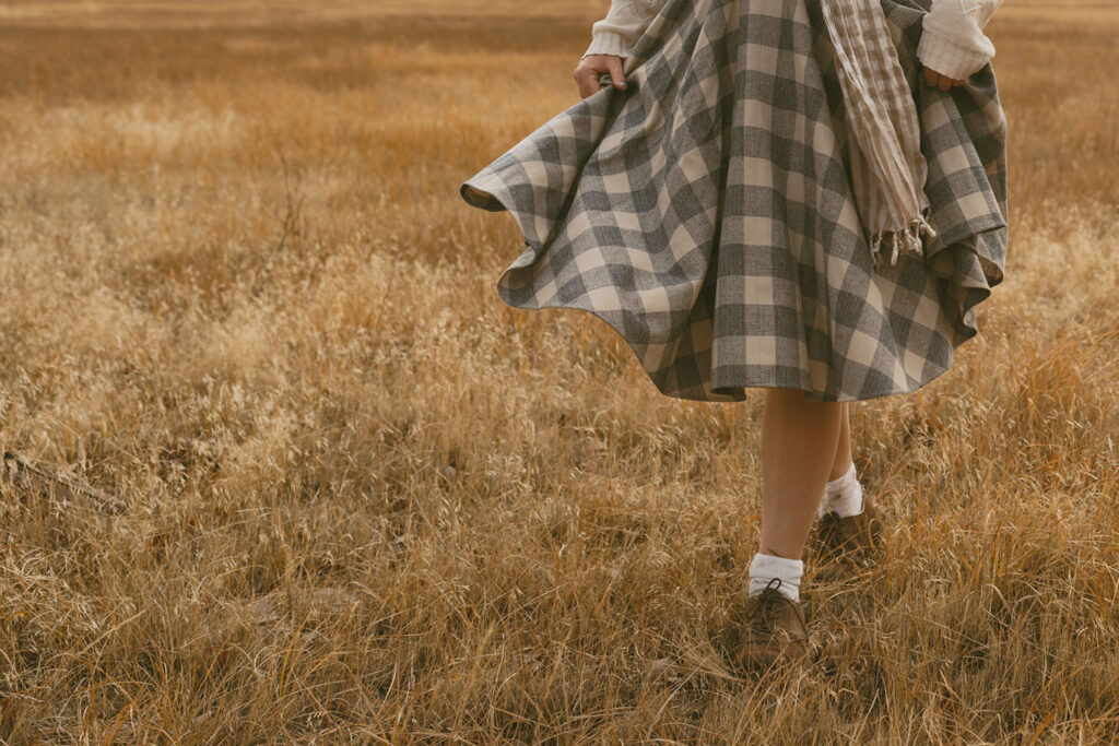 Flowing plaid skirt as the senior girl walks through the open field