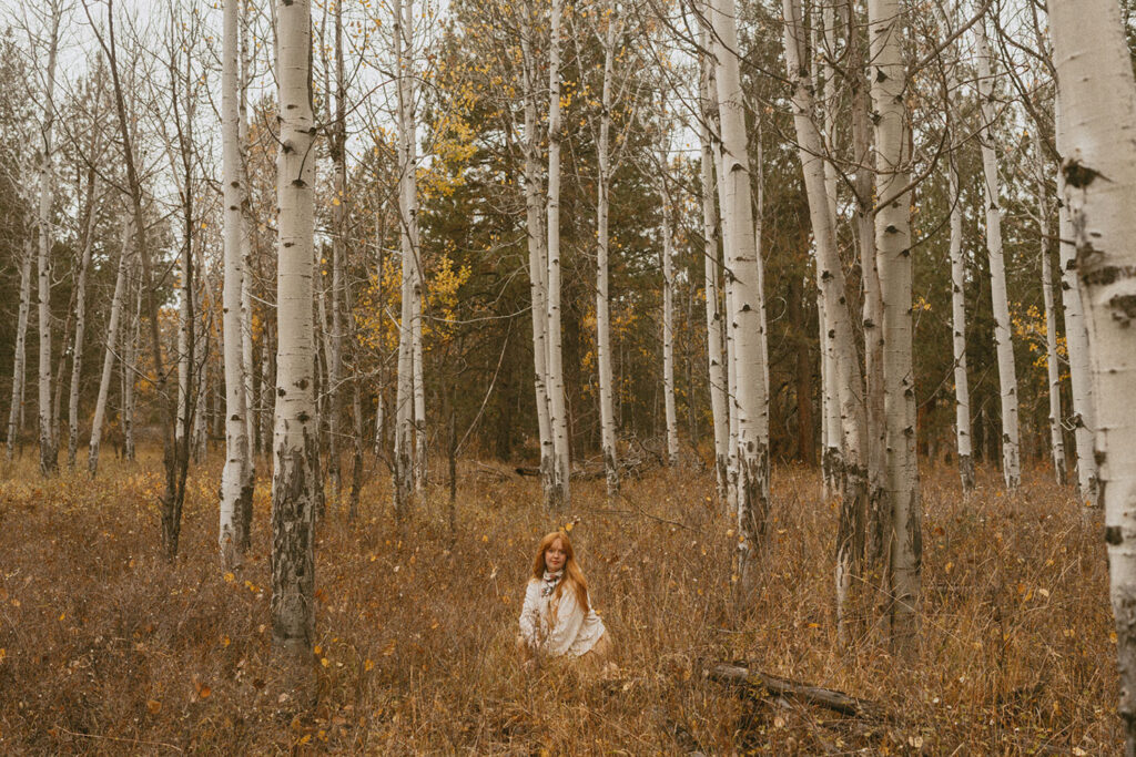 Senior girl sitting among the aspens for a photo session by a senior photographer in Bend