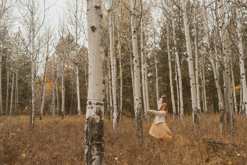 Senior girl twirling between aspen trees for a photo session by a senior photographer in Bend