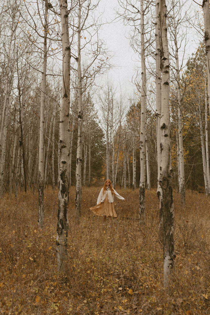 Senior girl twirling in a golden aspen grove, dress flowing with movement