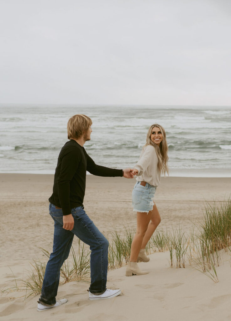 Callie and Nolan walking hand in hand by the beach