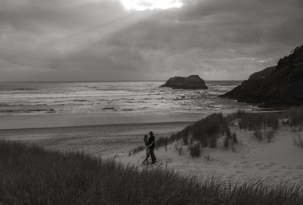 Callie and Nolan facing each other with the view of Haystack rock behind them