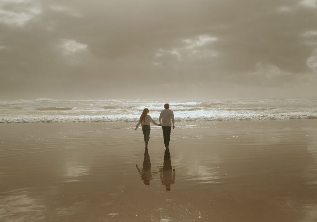 Callie and Nolan walking towards the beach during their beach engagement photo session