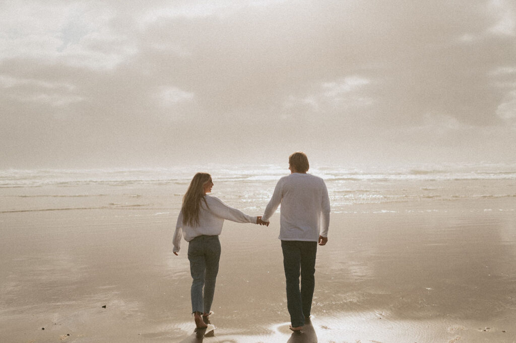 Callie and Nolan walking towards the beach holding each others hand