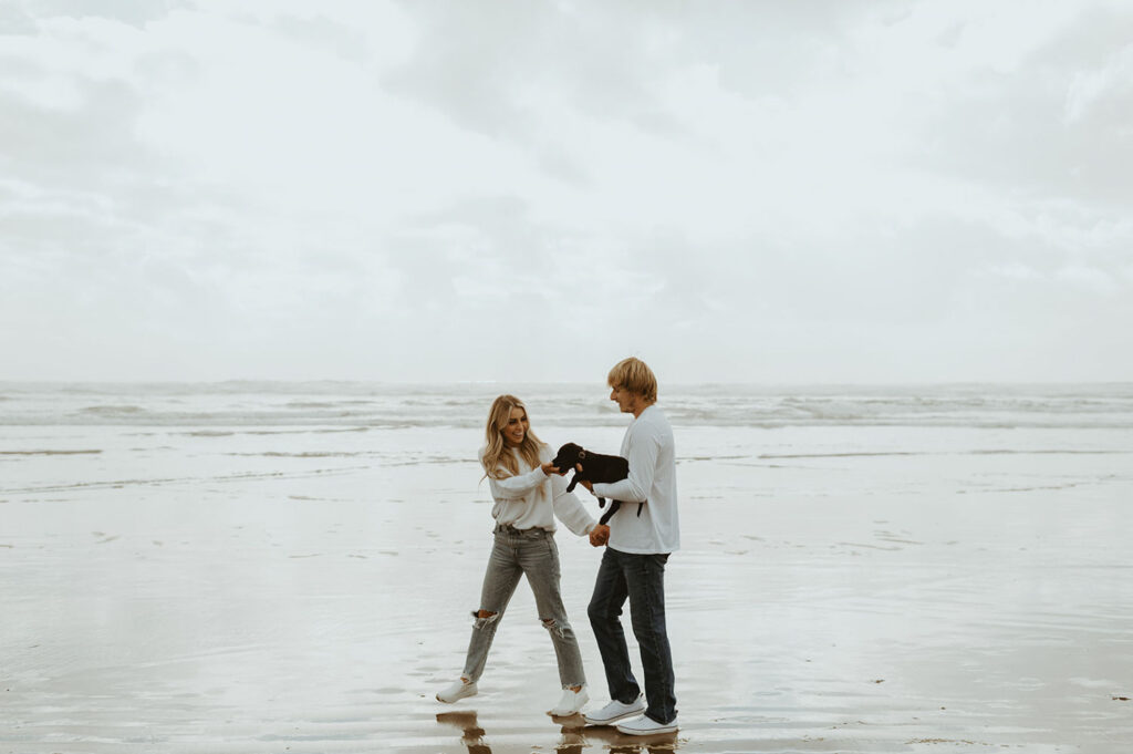 Callie and Nolan with their dog walking by the beach for their engagement photo