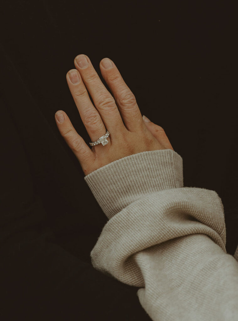 Close-up of Callie’s engagement ring on her hand, sleeve partially covering her fingers