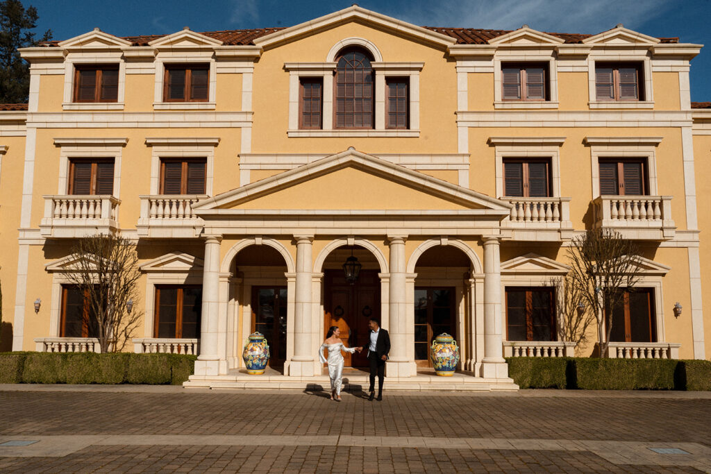 Two people standing in front of a large yellow building