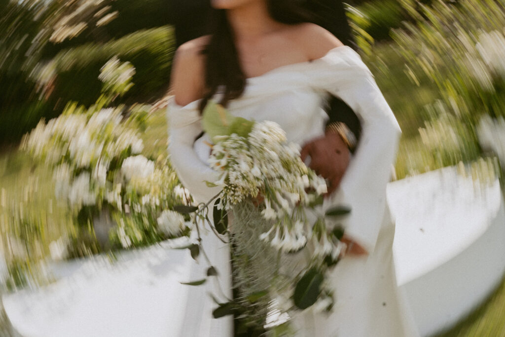 A bride in a white dress is holding a bouquet of white flowers.
