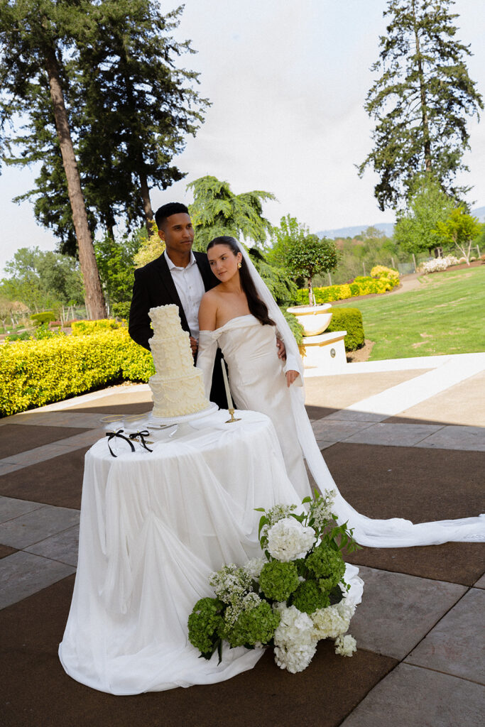 A bride and groom standing next to a cake on a table